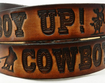 May include: Brown leather belt with the words "COWBOY UP!" embossed on it. The belt also features a silhouette of a cowboy riding a horse.