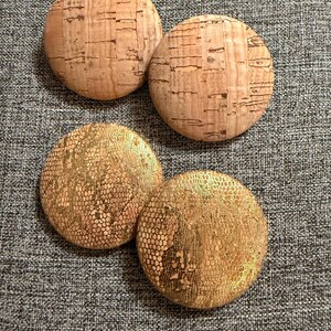May include: Four round cork coasters. Two coasters are plain cork and two coasters have a gold metallic pattern.