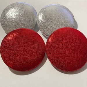 May include: Four round, decorative buttons. Two are silver with a textured surface and two are red with a textured surface.