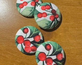 May include: Four round fabric buttons with a white background and a green and red holly berry design.