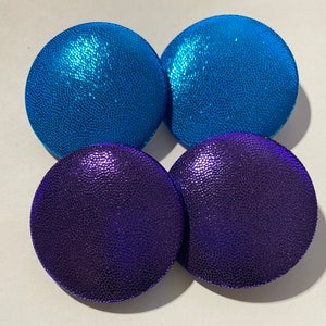 May include: Four round, decorative buttons with a textured surface. Two buttons are a vibrant blue color and two buttons are a deep purple color.