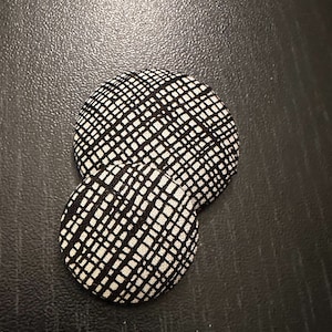 May include: Two round black and white patterned fabric buttons.
