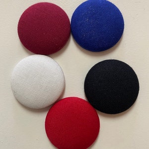 May include: Five fabric covered buttons in different colors: maroon, blue, white, black, and red.
