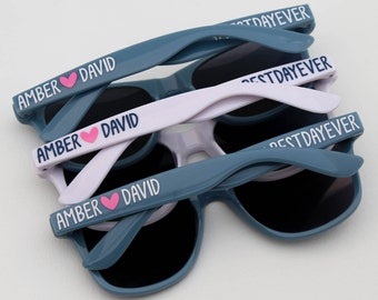 May include: Three pairs of blue and white sunglasses with the text "Amber ♥ David" and "Best Day Ever" printed on the frames.
