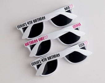 May include: Three white plastic sunglasses with black lenses. The sunglasses have personalized text, including "Olivia's 4th Birthday", "Birthday Girl", "Mia", "Olivia", and "Ella".