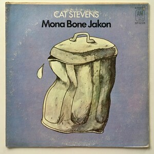 May include: A vintage vinyl record album cover featuring a drawing of a crushed metal trash can with a single teardrop falling from it. The album title "Mona Bone Jakon" is printed in black text on a light blue background. The artist's name "Cat Stevens" is printed in black text above the album title. The record label "A&M Records" is printed in the upper right corner of the cover.