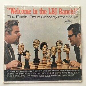May include: A vintage vinyl record album cover featuring a caricature of Lyndon B. Johnson on a chessboard with other political figures. The album title is "Welcome to the LBJ Ranch!" and the subtitle is "The Robin-Doud Comedy Interviews".