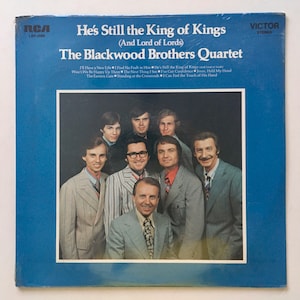 May include: A vintage vinyl record album cover featuring a group of men in suits. The album is titled "He's Still the King of Kings (And Lord of Lords)" by The Blackwood Brothers Quartet. The album cover is blue and features the RCA Victor logo.