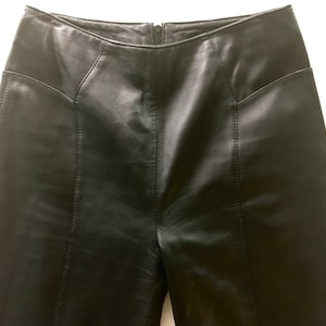 Puede incluir: Pantalones de cuero negro de cintura alta y pierna recta.