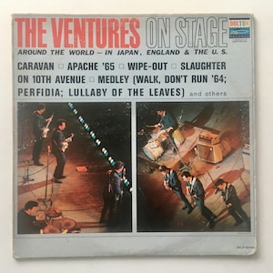 May include: Vintage album cover for "The Ventures On Stage." The cover features a photo of the band performing live, with the album title in red and white text. Song titles are listed below the band's name.