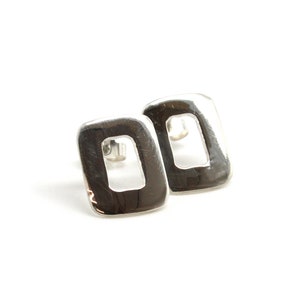 May include: A pair of silver earrings with a rectangular shape and a cutout in the center.