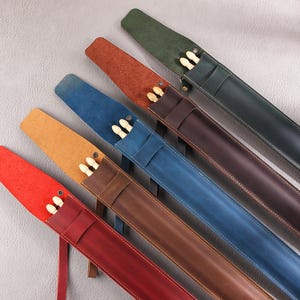 May include: Six leather drum stick cases in different colors, including red, brown, blue, green, and tan. The cases are lined with soft fabric and have a zipper closure. Each case holds a pair of drum sticks.