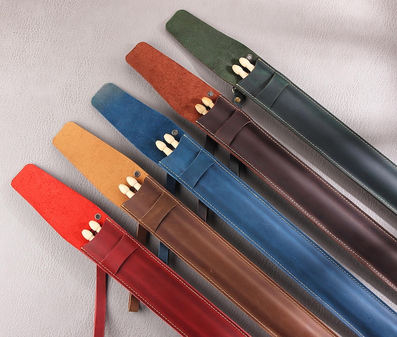 May include: Six leather drum stick cases in different colors, including red, brown, blue, green, and tan. The cases are lined with soft fabric and have a zipper closure. Each case holds a pair of drum sticks.