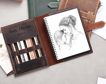 May include: A brown leather journal with a spiral bound sketchbook inside. The journal has a pocket on the front with a pencil holder and the text "Amelia & Brooklyn May 10, 2025" is engraved on the front.
