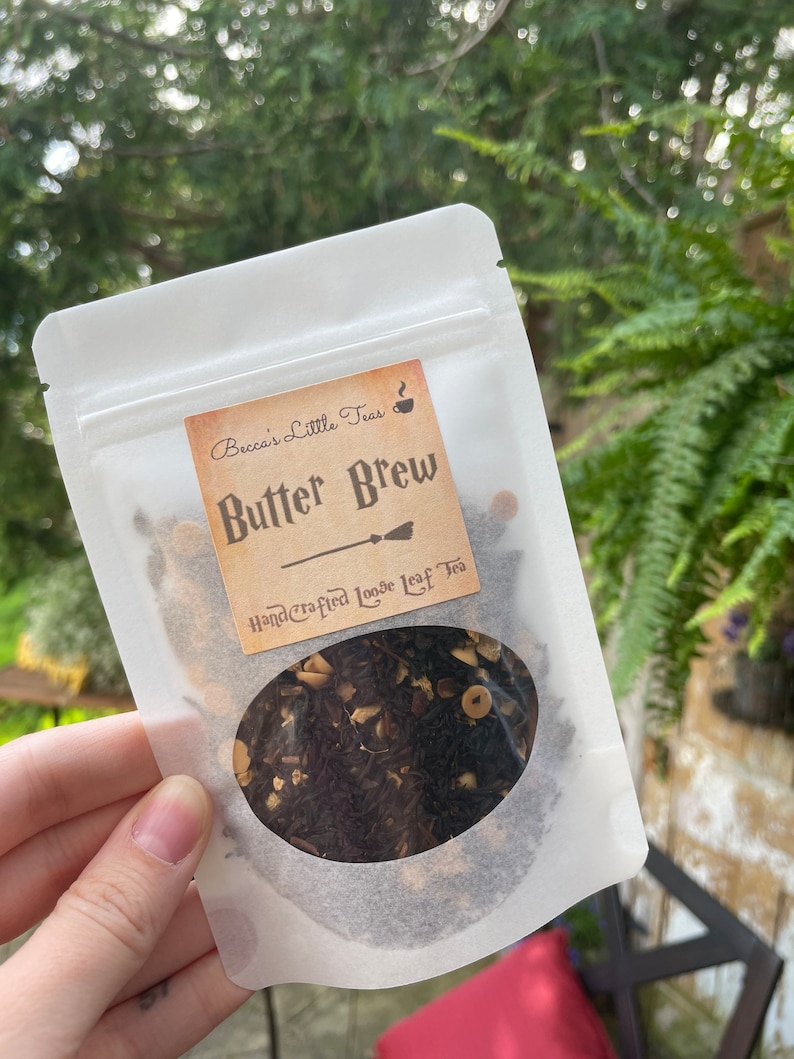 May include: A white resealable pouch with a label that reads "Becca's Little Teas" and "Butter Brew Handcrafted Loose Leaf Tea". The pouch contains loose leaf tea with brown, black, and white pieces.