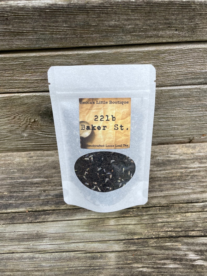 May include: A white pouch with a label that reads "Becca's Little Boutique 221b Baker St. Handcrafted Loose Leaf Tea". The pouch contains loose leaf tea.