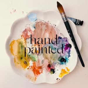 a plate with a paintbrush and the words hand painted on it