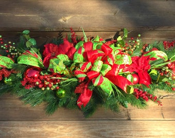 May include: A Christmas garland with red and green ribbon, red poinsettias, and red and green ornaments.