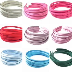 Può includere: Un set di dieci fasce per capelli lisce in vari colori, tra cui bianco, rosa, rosso, rosa chiaro, blu chiaro e verde scuro.