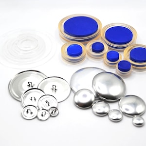 May include: Assortment of silver metal button blanks and clear plastic button molds with blue plastic inserts.