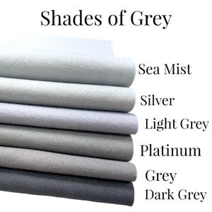 May include: A selection of grey felt fabric swatches, ranging from pale to dark tones. The image features the text "Shades of Grey" and colour names: Sea Mist, Silver, Light Grey, Platinum, Grey, and Dark Grey. Ideal for craft projects.