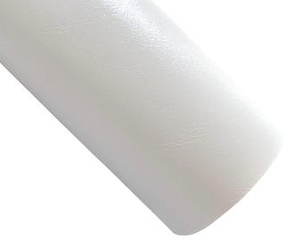 May include: A roll of white, textured material, possibly leather or vinyl, is angled across the frame. The material has a subtle sheen, reflecting light. The surface appears smooth with a slight grain.