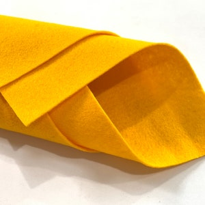 Könnte beinhalten: Eine Rolle leuchtend gelber Filzstoff. Der Filz ist weich und glatt und perfekt für Bastelarbeiten.