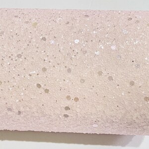 May include: A sheet of pink glitter fabric with a fine, speckled texture. The glitter is a light, iridescent white.