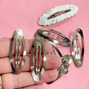 以下が含まれることがあります： 銀色の楕円形のヘアクリップのセット。クリップは滑らかで光沢のある仕上げで、髪を所定の位置に保持するように設計されています。