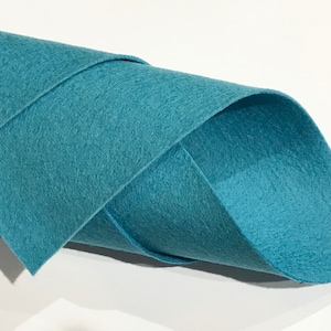 Op de afbeelding: Een rol tealkleurige viltstof. De stof is zacht en glad, en perfect voor knutselprojecten.