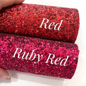 Könnte beinhalten: Zwei Rollen Glitzerstoff, eine rote und eine rubinrote. Der Stoff ist strukturiert und glitzert.