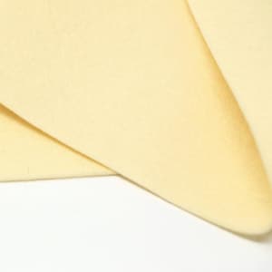 May include: A close-up of a pale yellow fabric, showing the texture and colour of the material.