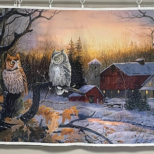 May include: A rectangular fabric panel featuring a winter landscape with two owls perched on a tree branch in the foreground. The scene includes a red barn, a stone silo, and snow-covered ground under a sunset sky with orange and purple hues.