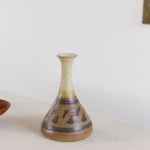 May include: A brown and white ceramic vase with a geometric pattern. The vase has a narrow neck and a wide base.