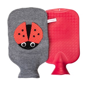 Op de afbeelding: Een grijze warmwaterkruik met een rood lieveheersbeestje ontwerp aan de voorkant. De kruik is gemaakt van rubber en heeft een rode dop. De tekst "Treasured Keepsake" is op de kruik gedrukt.