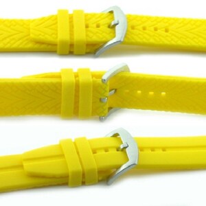 May include: A bright yellow rubber watch strap with a silver buckle. The strap has a textured pattern.