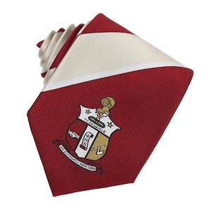 May include: Red and white striped necktie with a crest featuring a shield with the text "T.C.E.WOLFS" and "ΦΔΝΗ" in gold lettering. The crest also includes a green leaf and a gold anchor.