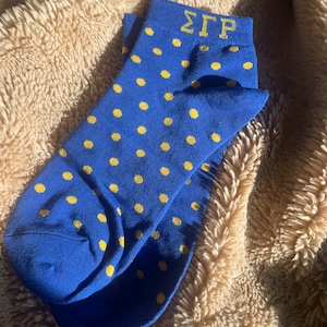 May include: A pair of blue socks with yellow polka dots and the letters "ΣΓΡ" in yellow on the top of one sock.