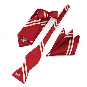 May include: A set of three red and white striped neckties. The set includes a bow tie, a regular tie, and a pocket square. All three items feature a white crest with a red and gold design.