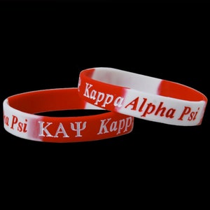 May include: Two red and white silicone bracelets with the text "Kappa Alpha Psi" and "ΚΑΨ Kapp" in white lettering.