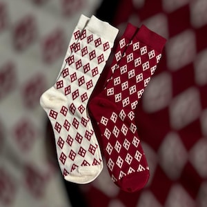 May include: Two pairs of socks, one cream-colored and one burgundy, are displayed. Both socks feature a repeating pattern of white diamonds with burgundy accents. The socks are made of a soft material and are suitable for everyday wear.