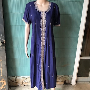 May include: A long, navy blue dress with a gold embroidered design. The dress has a round neckline and short sleeves.