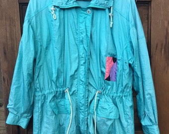 May include: A turquoise blue jacket with a drawstring waist and a patch on the left side. The jacket has a zipper closure and a label that reads "Hot Spices".