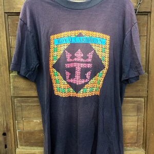May include: A dark blue t-shirt with a colorful graphic of a crown and the text "ROYAL CARIBBEAN" in a checkered pattern.