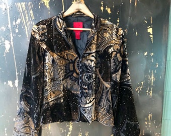 May include: A black velvet jacket with a gold paisley pattern and a red tag. The jacket has a button closure and long sleeves.