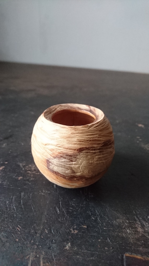 A hand-carved yew vessel with raw tactile texture — the kind of object you pick up and can't put down.