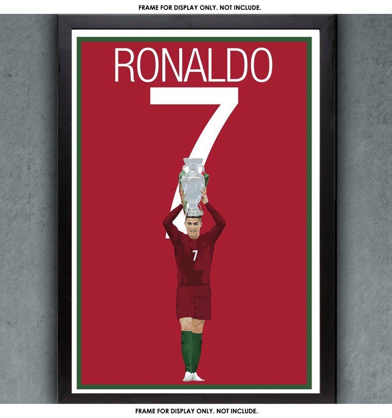 K&ouml;nnte beinhalten: Gerahmter Druck mit Cristiano Ronaldo, der eine Troph&auml;e h&auml;lt. Der Hintergrund ist rot mit dem Namen "RONALDO" und der Zahl "7" in Wei&szlig;. Der Spieler tr&auml;gt eine weinrote Uniform mit gr&uuml;nen Socken.