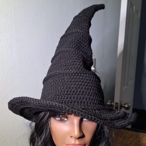 May include: A black crocheted witch hat with a tall, pointed crown and a wide brim.