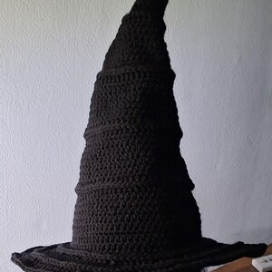 May include: A black crocheted witch hat with a tall, pointed crown and a wide brim.