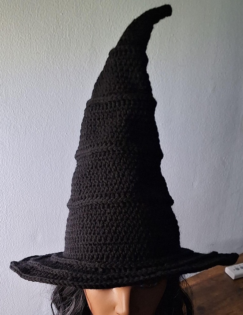 May include: A black crocheted witch hat with a tall, pointed crown and a wide brim.